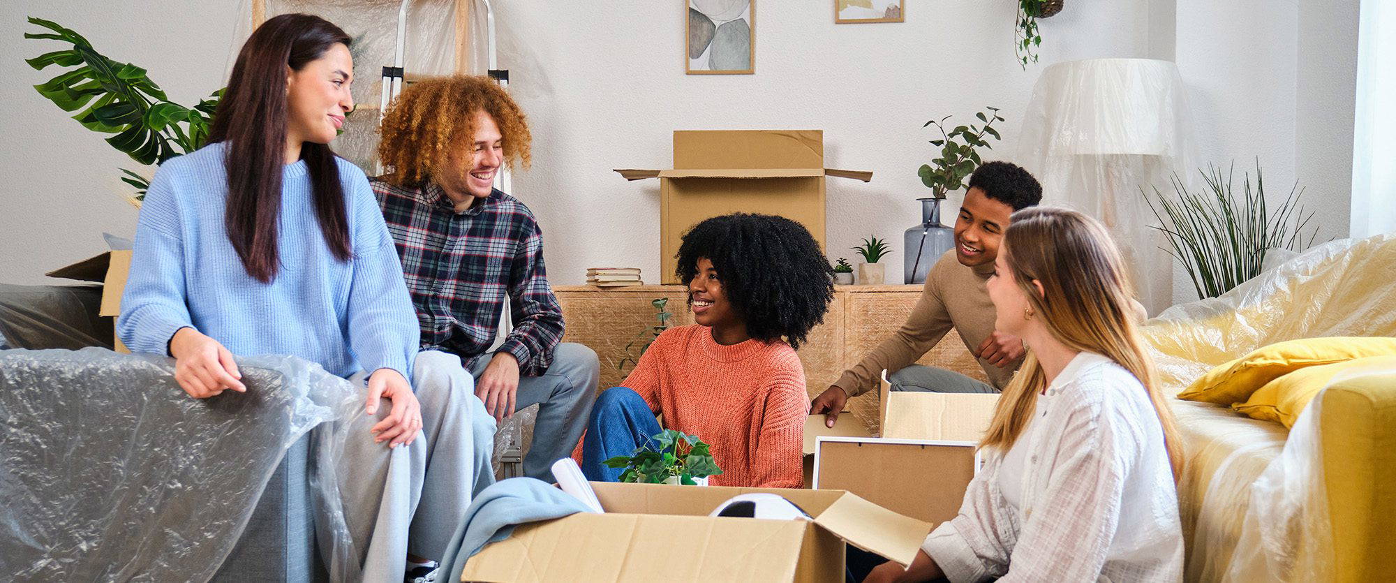 Group of students unpacking boxes together in shared student accommodation.